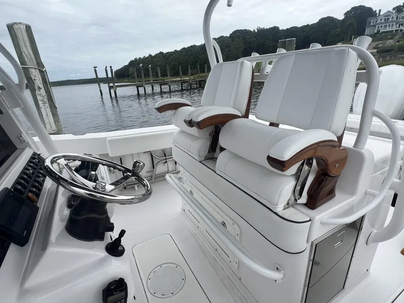 Slide: The Image of 2019 Southport 33 FE boat interior with white seating and steering wheel by the water. - 15