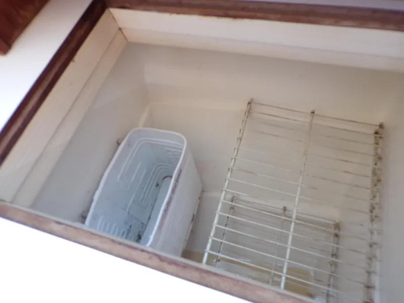 Slide: The Image of Empty storage compartment in a 1991 Catalina 34 boat, featuring wire racks and a plastic bin. - 13