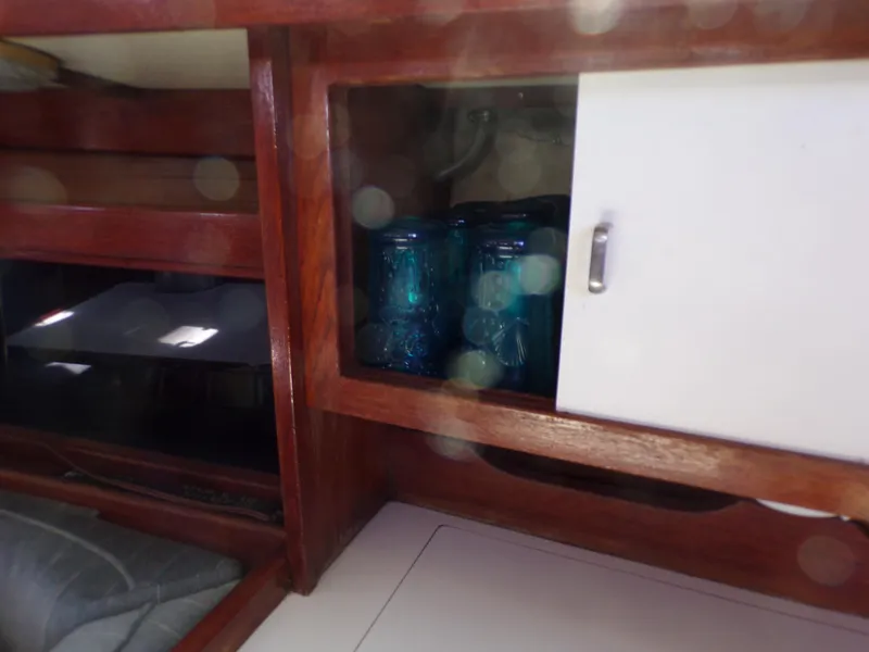 Slide: The Image of Wooden cabinet interior of 1991 Catalina 34 sailboat with blue jars inside. - 14