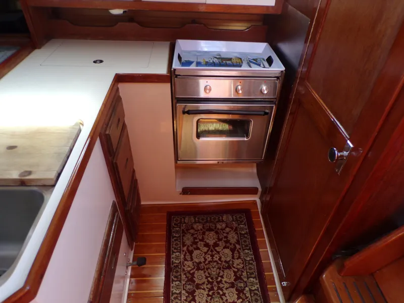 Slide: The Image of 1991 Catalina 34 yacht interior with stove, wooden cabinetry, and patterned rug. - 17