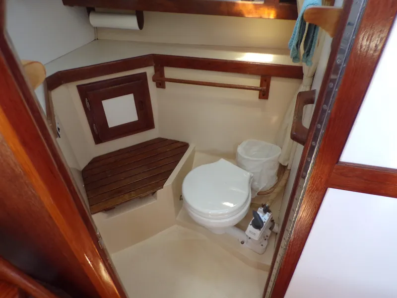 Slide: The Image of 1991 Catalina 34 boat bathroom with toilet, wooden seat, and storage shelf. - 18
