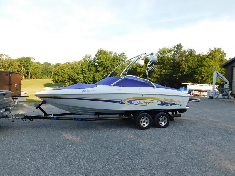 Slide: The Image of 2002 Baja 212 Islander boat on trailer, parked outdoors with trees in background. - 0