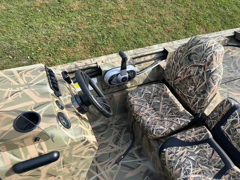 Slide: The Image of 2025 Lowe Roughneck 1760SC boat interior with camo seats and steering console. - 15