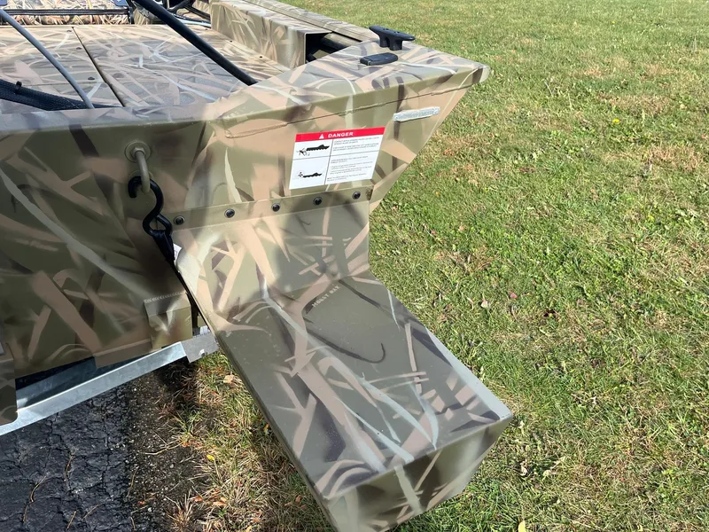 Slide: The Image of 2025 Lowe Roughneck 1760SC boat with camouflage design on grassy area. - 20