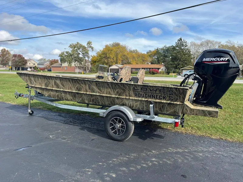 Slide: The Image of 2025 Lowe Roughneck 1760SC boat on trailer with Mercury outboard, parked outdoors. - 4