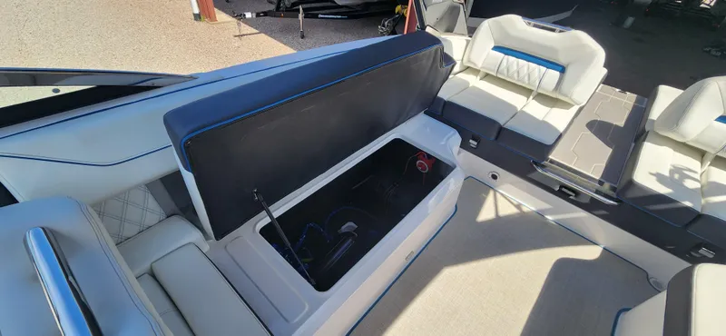 Slide: The Image of 2021 Regal LS6 Surf boat interior with open storage compartment and white seating. - 11