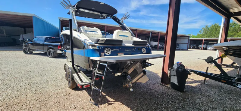 Slide: The Image of 2021 Regal LS6 Surf boat in storage, rear view with blue accents. - 3