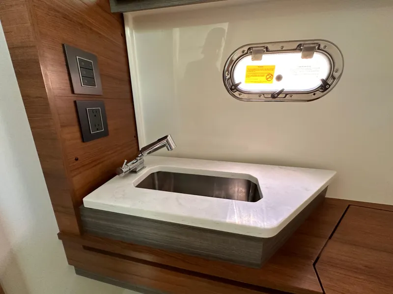Slide: The Image of 2021 Tiara Sport 34 LS yacht interior with modern sink and porthole window. - 28