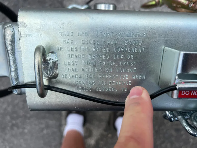 Slide: The Image of Close-up of 2024 trailer brake actuator with safety instructions and a person's finger pointing. - 1