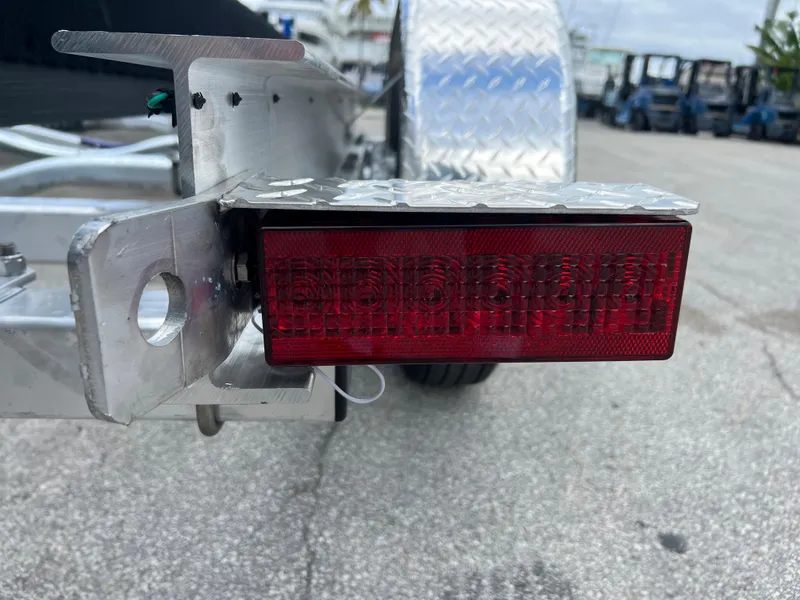 Slide: The Image of Close-up of a 2024 trailer's red taillight and metal frame on a paved surface. - 10
