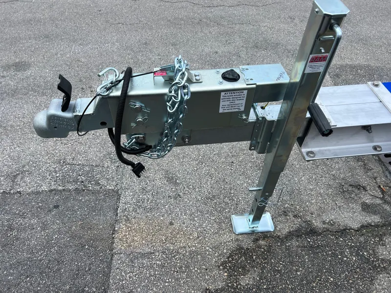 Slide: The Image of 2024 trailer hitch with safety chain and jack stand on asphalt. - 4