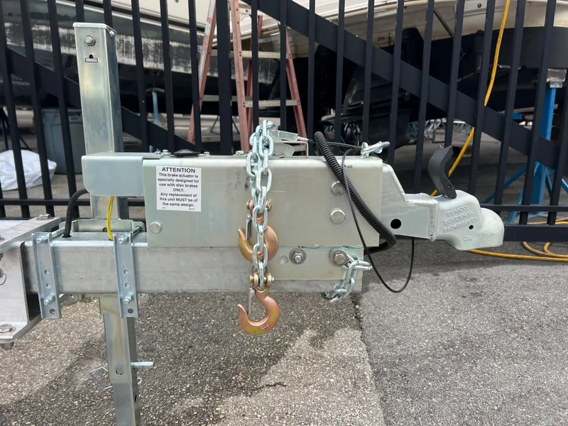 Slide: The Image of 2024 trailer hitch with safety chains and hooks, parked near a metal fence. - 7