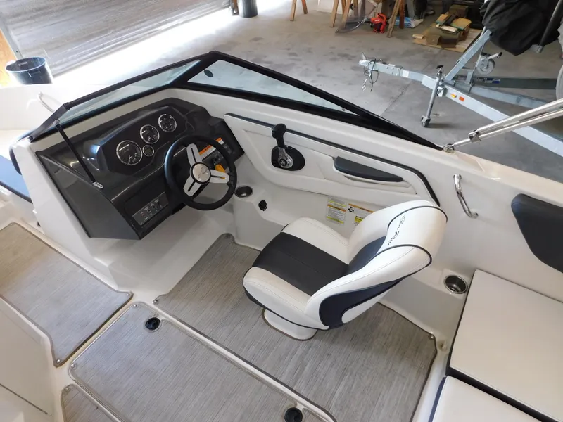 Slide: The Image of 2015 Sea Ray 19 SPX boat interior with steering wheel and seating in a garage. - 16