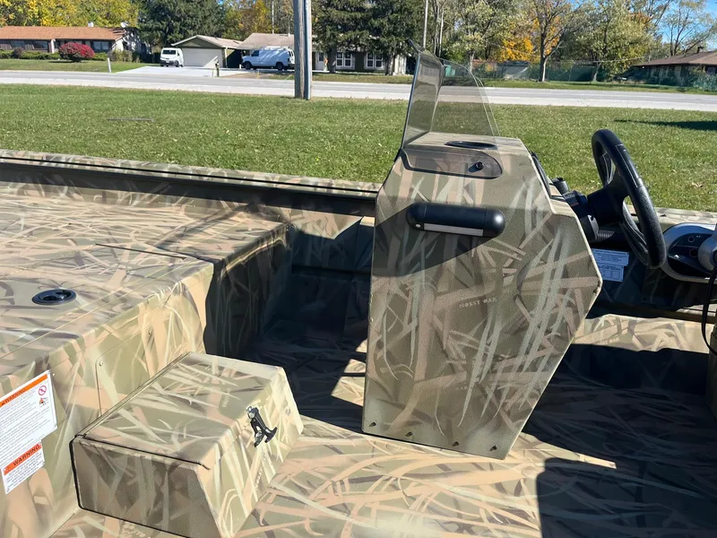 Slide: The Image of 2025 Lowe Roughneck 1760SC boat with camouflage design, parked outdoors. - 12