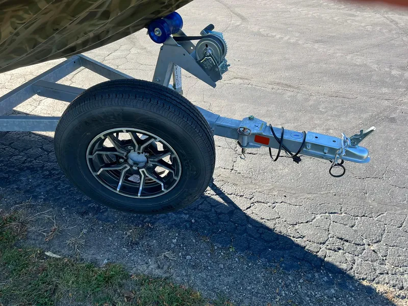 Slide: The Image of Trailer hitch and wheel of 2025 Lowe Roughneck 1760SC boat on pavement. - 19
