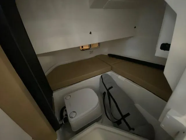 Slide: The Image of 2024 Sea Ray SDX 250 Outboard cabin interior with seating and compact toilet. - 14