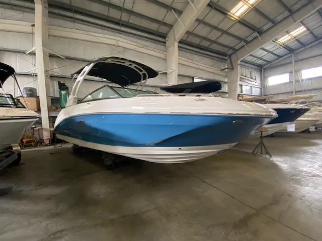 Slide: The Image of 2024 Sea Ray SDX 250 Outboard boat in a showroom, featuring a sleek blue and white design. - 2