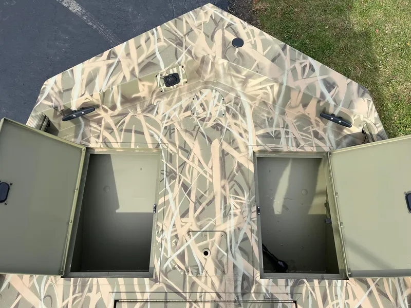 Slide: The Image of 2025 Lowe Roughneck 1860 Tunnel Jet boat with camo design and open storage compartments. - 11