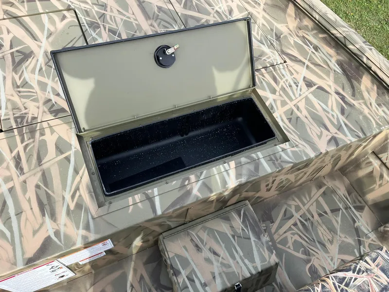 Slide: The Image of 2025 Lowe Roughneck 1860 Tunnel Jet boat with open storage compartment, camo design. - 16