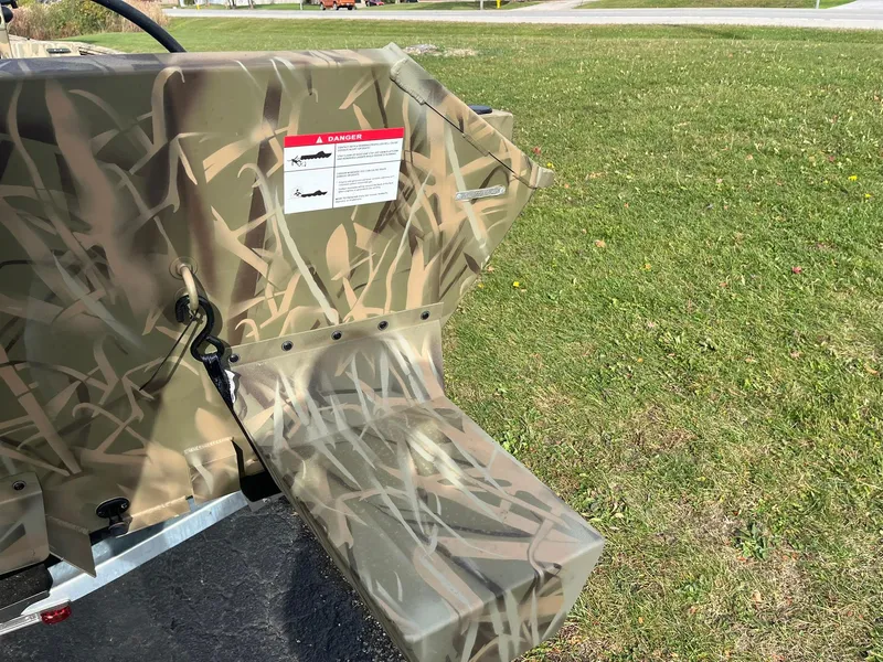 Slide: The Image of 2025 Lowe Roughneck 1860 Tunnel Jet boat with camouflage design on grass. - 20