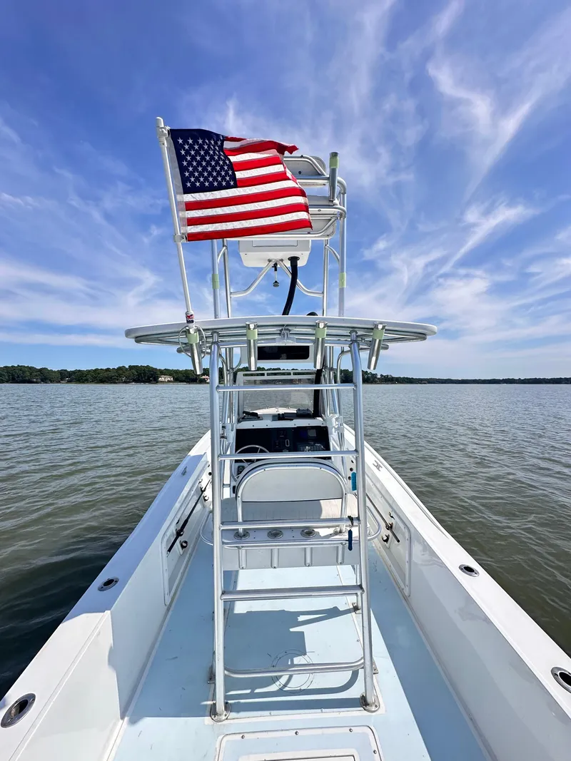 Slide: The Image of 1995 Mako 221 B Classic Center Console boat with American flag on calm water. - 2