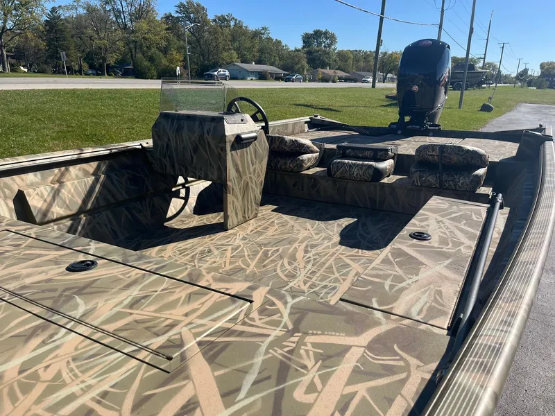 Slide: The Image of 2025 Lowe Roughneck 2070 SC boat with camouflage design, parked on a sunny day. - 11