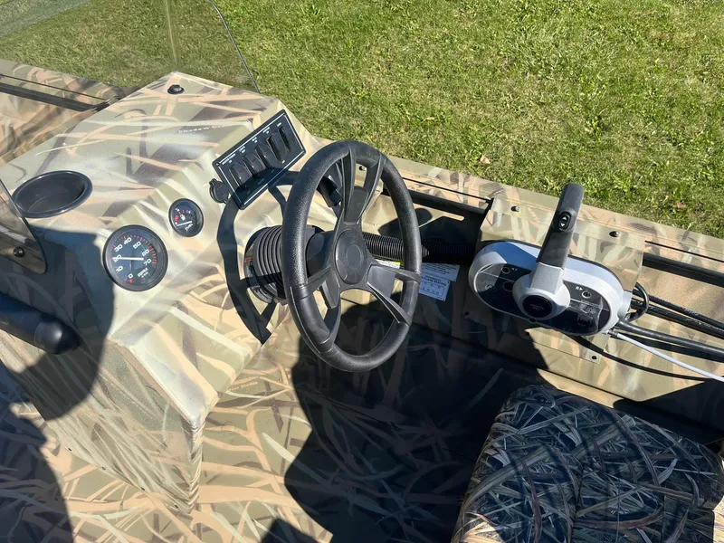 Slide: The Image of 2025 Lowe Roughneck 2070 SC boat interior with camo design and steering console. - 17
