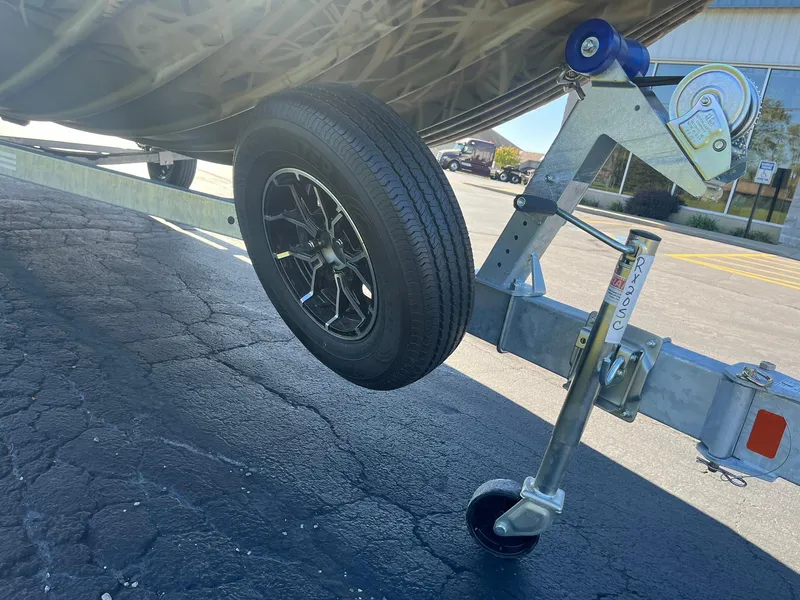 Slide: The Image of 2025 Lowe Roughneck 2070 SC trailer wheel on asphalt, showcasing sturdy design and durability. - 22