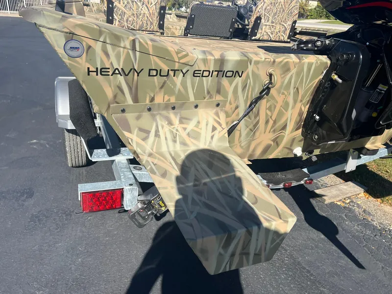 Slide: The Image of 2025 Lowe Roughneck 2070 SC boat, camo design, "Heavy Duty Edition" text, on a trailer. - 7