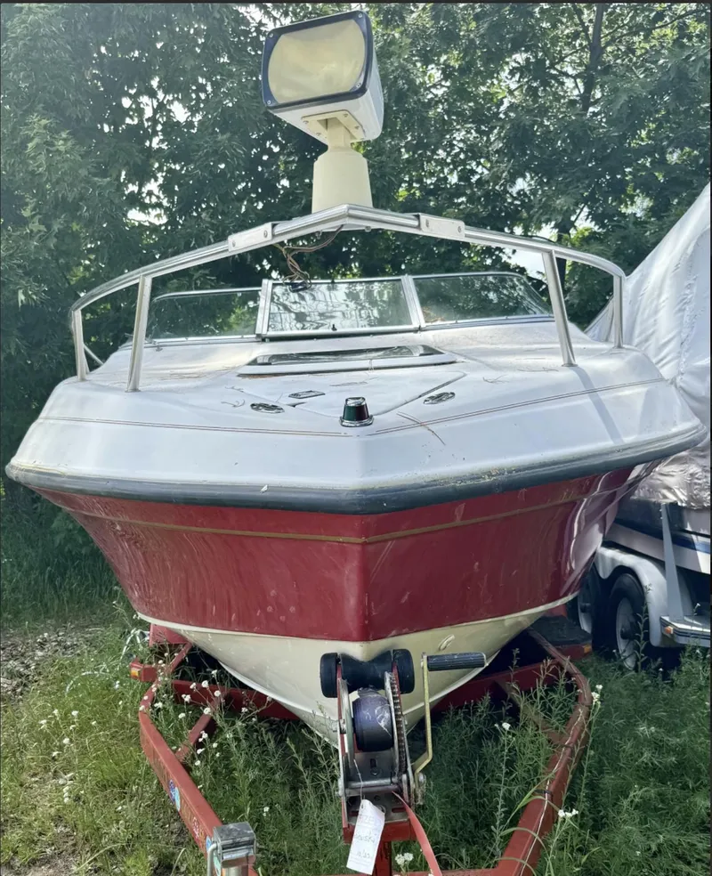 Slide: The Image of 1992 Crownline 210 CCR boat on trailer, parked outdoors with greenery. - 3