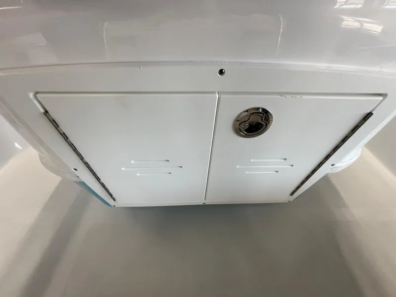 Slide: The Image of 2025 NauticStar 194 Bay boat storage compartment with latch, white interior. - 10
