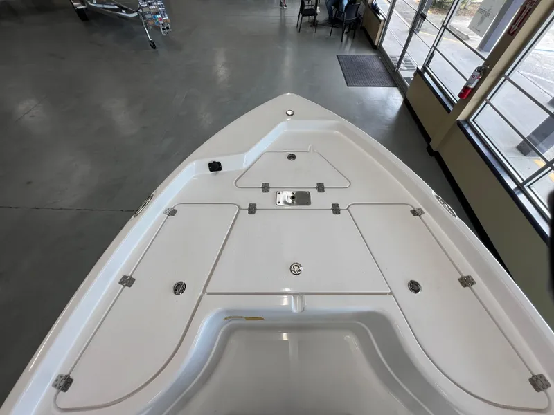 Slide: The Image of 2025 NauticStar 194 Bay boat deck in showroom, featuring storage compartments and sleek design. - 24