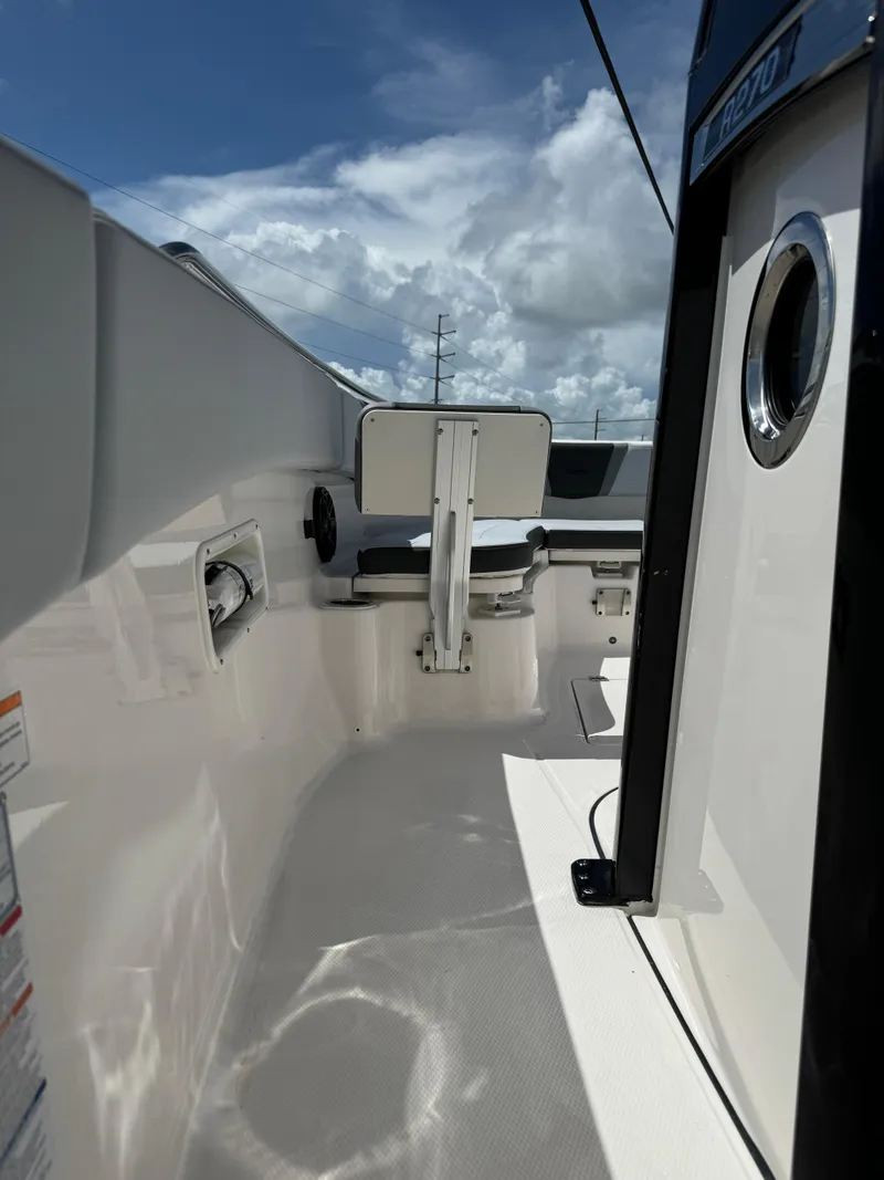Slide: The Image of 2025 Robalo R270 Center Console boat interior with seating, under a partly cloudy sky. - 21