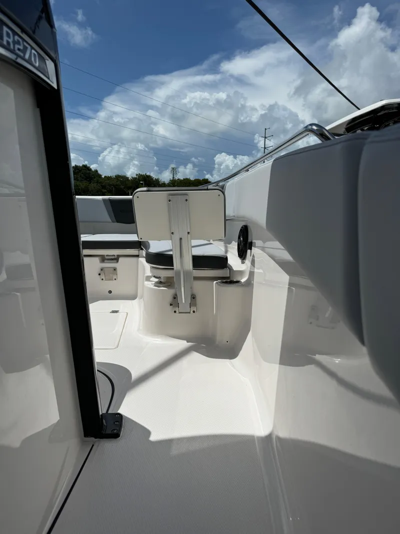 Slide: The Image of 2025 Robalo R270 Center Console boat interior with seating, under a partly cloudy sky. - 22