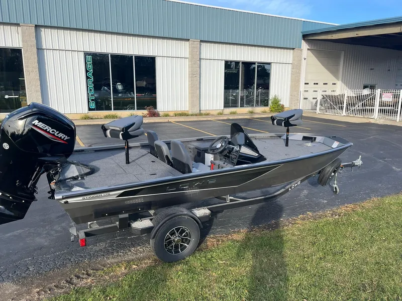 Slide: The Image of 2025 Lowe Stinger 175C fishing boat with Mercury engine, parked outside a storage facility. - 2