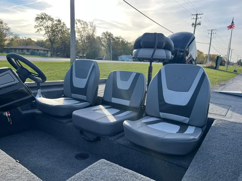 Slide: The Image of 2025 Lowe Stinger 175C boat interior with three gray seats, steering wheel, and outboard motor. - 8