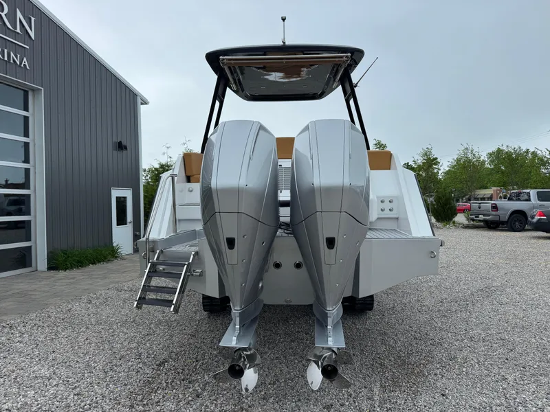 Slide: The Image of 2025 Iguana Bow Rider boat with dual outboard motors, parked on gravel near a building. - 4