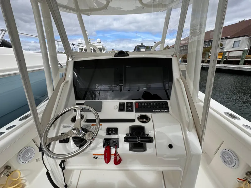 Slide: The Image of 2018 Regulator 28 boat console with steering wheel and controls, docked at marina. - 16