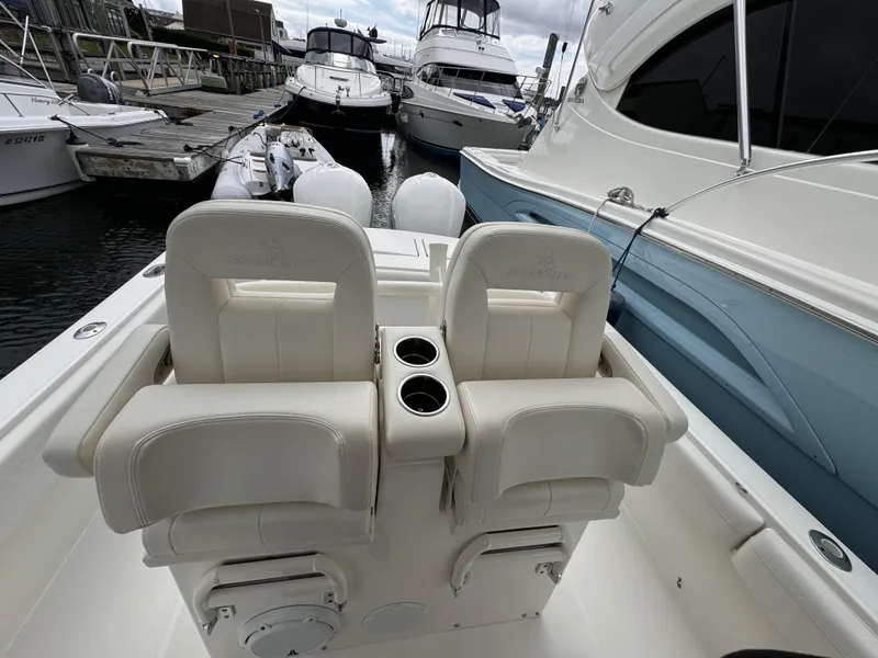 Slide: The Image of 2018 Regulator 28 boat with dual seats and cup holders at a marina. - 18