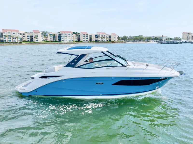 Slide: The Image of 2020 Sea Ray Sundancer 320 cruising on a sunny day near waterfront buildings. - 2