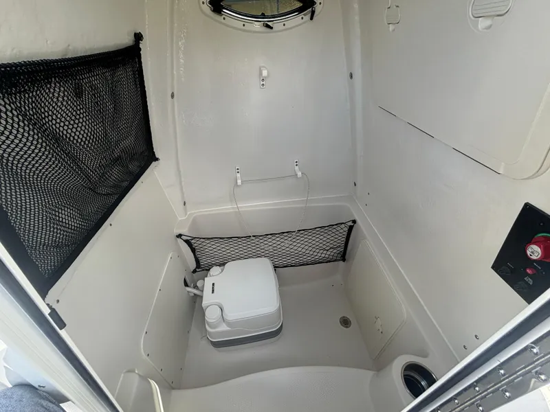 Slide: The Image of 2025 Sailfish 241 CC boat interior with portable toilet and storage nets. - 15