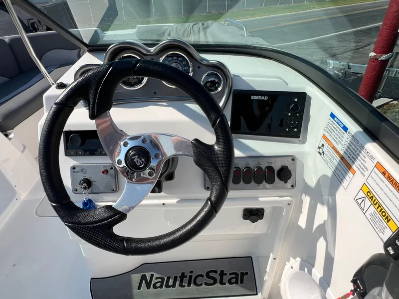 Slide: The Image of 2023 NauticStar 203 DC boat dashboard with steering wheel and control panel. - 8
