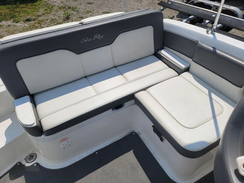 Slide: The Image of 2011 Sea Ray 240 Sundeck boat seating area with white and gray upholstery. - 17