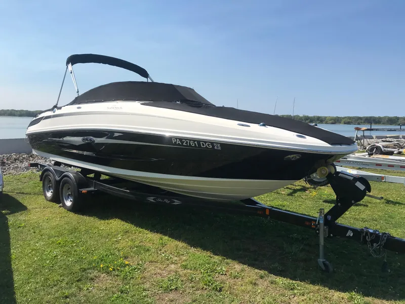 Slide: The Image of 2011 Sea Ray 240 Sundeck boat on trailer, parked on grass near water. - 7