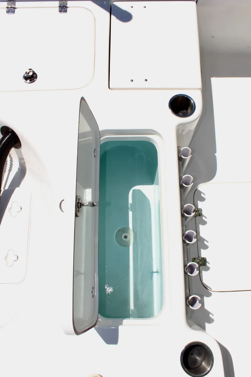 Slide: The Image of 2025 Sea Pro 230 Bay boat interior with open storage compartment and cup holders. - 16