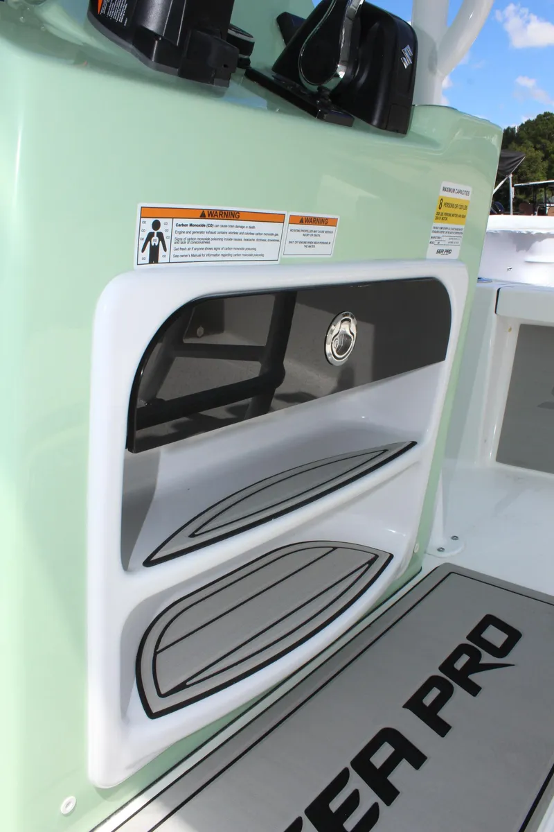 Slide: The Image of 2025 Sea Pro 230 Bay boat console with storage compartments and safety labels. - 28