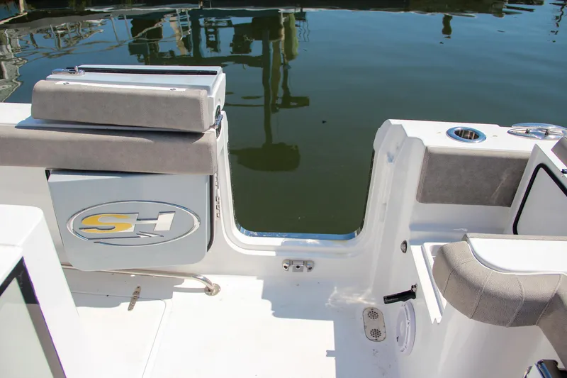 Slide: The Image of Sea Hunt Gamefish 28 boat interior, 2025 model, featuring seating and storage by the water. - 13