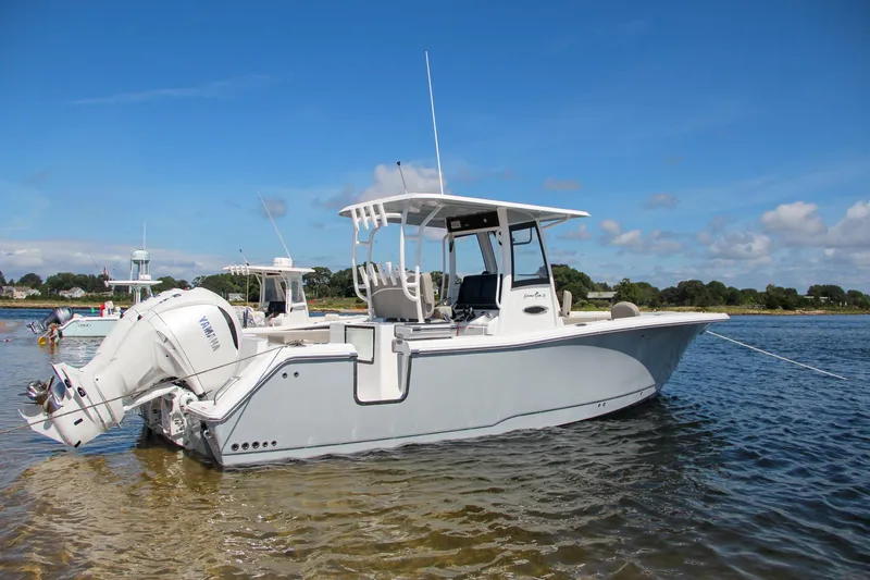 Slide: The Image of 2025 Sea Hunt Gamefish 28 boat anchored in shallow water under a clear blue sky. - 2