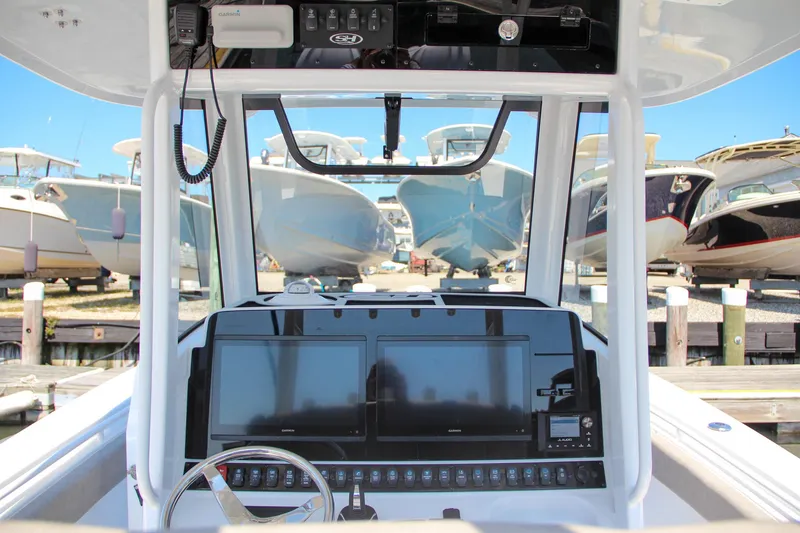 Slide: The Image of 2025 Sea Hunt Gamefish 28 dashboard with dual screens, docked boats in background. - 29
