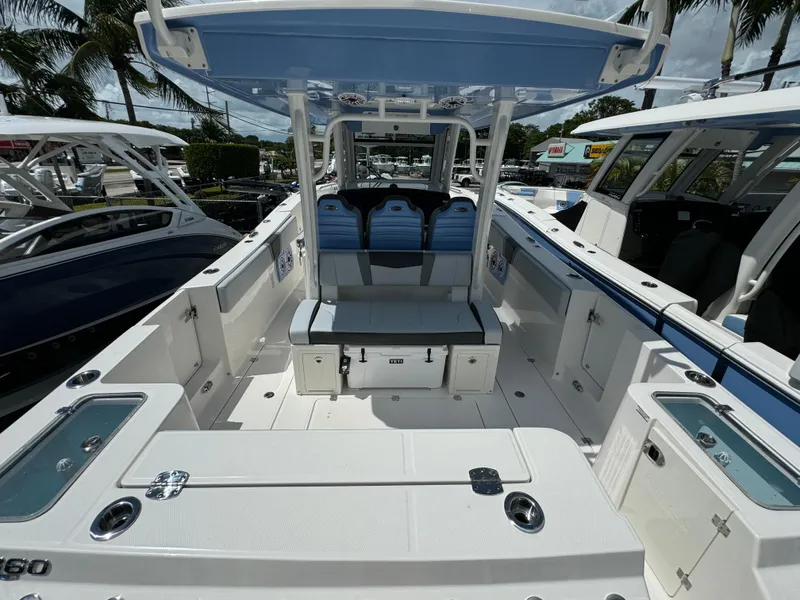 Slide: The Image of 2025 Robalo R360 Center Console boat with spacious deck and seating, docked under palm trees. - 5